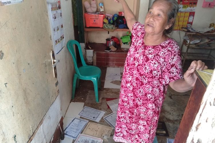 Sri mengeringkan ijazah milik cucu dan anaknya yang terendam banjir di Jatipadang, Senin (1/4/2019)