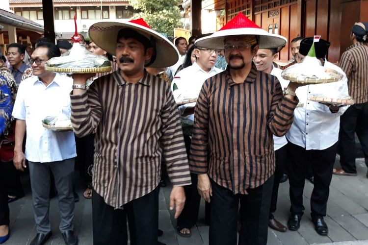 Wali Kota Surakarta FX Hadi Rudyatmo dan Wakil Wali Kota Achmad Purnomo membawa tumpeng dalam kirab 1001 tumpeng bentuk kegembiraan terpilihnya pasangan Jokowi-Maruf Amin sebagai presiden dan wakil presiden RI periode 2019-2024 di Solo, Jawa Tengah, Kamis (23/5/2019).