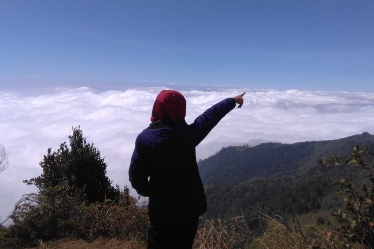 Wisatawan Berfoto dengan background serakan awan di Puncak Gunung Prau