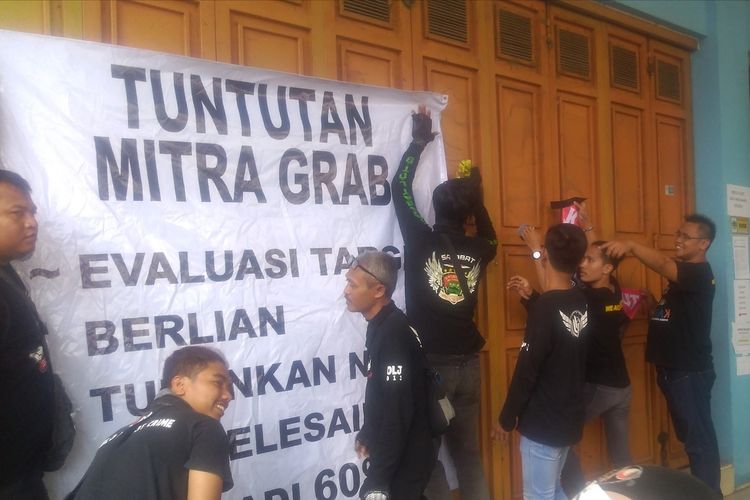Pengemudi ojol yang tergabung dalam Driver Ojol Banyumas Raya Kompak memasang spanduk tuntutan di depan kantor Grab Jalan Kolonel Sugiono Purwokerto, Jawa Tengah, Rabu (21/8/2019).