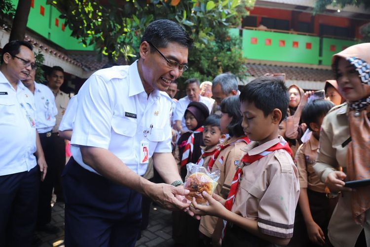 Kepala Dinas Pendidikan DKI Jakarta Ratiyono memberikan makanan kepada murid SD 03 dan 04 Penjaringan dalam rangka launching program Pemberian Penyediaaan Makanan Tambahan Anak Sekolah (PMTAS), Rabu (27/3/2019). 