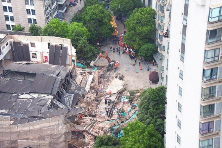 Alat berat dikerahkan untuk mencari korban yang tertimbun setelah bangunan di Shanghai, China, runtuh Kamis (16/5/2019).