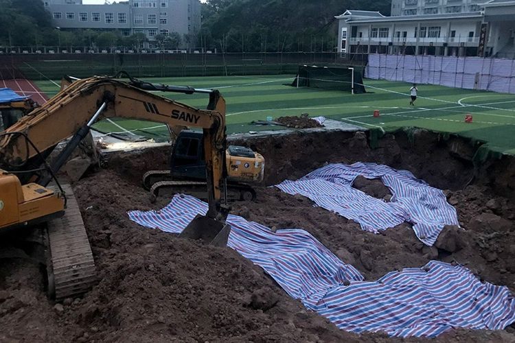 Proses penggalian lapangan olahraga untuk mencari jasad Deng Shiping