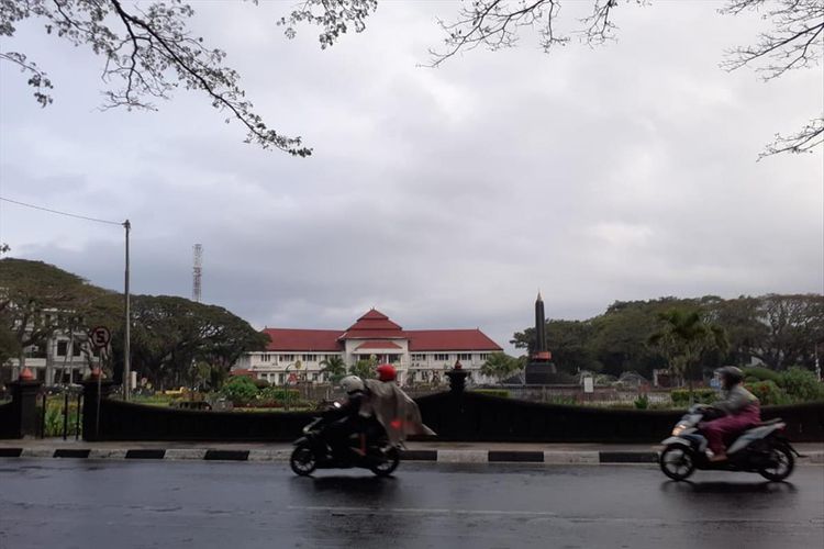Pengendara melintas di Bundaran Tugu Kota Malang saat turun gerimis, Jumat (5/7/2019)