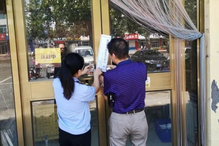 Dua petugas dari otoritas pengawas pasar Provinsi Shandong, China, memberi segel penutupan sebuah restoran setelah ketahuan mencuci piring menggunakan air kotor dalam video yang viral.