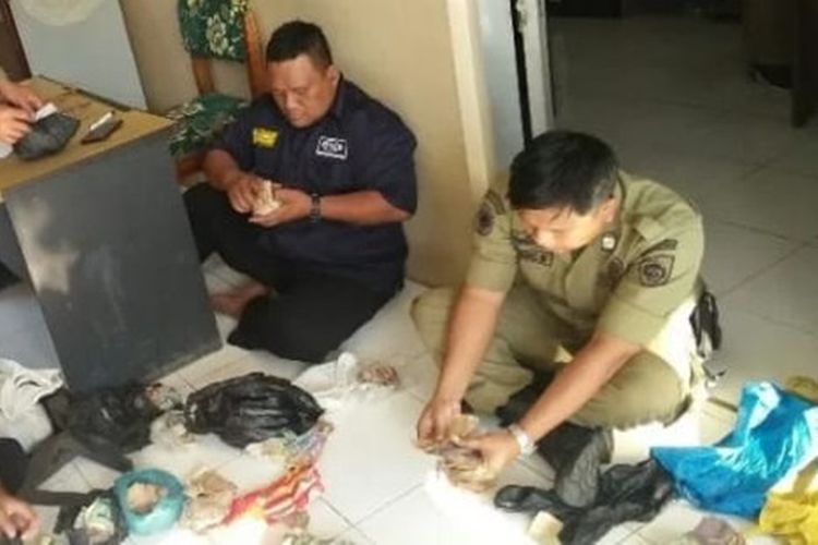 Petugas Satpol PP Sragen menghitung uang yang berada di tas milik Mbah Cipto senilai Rp 12 juta di Sragen, Jawa Tengah.