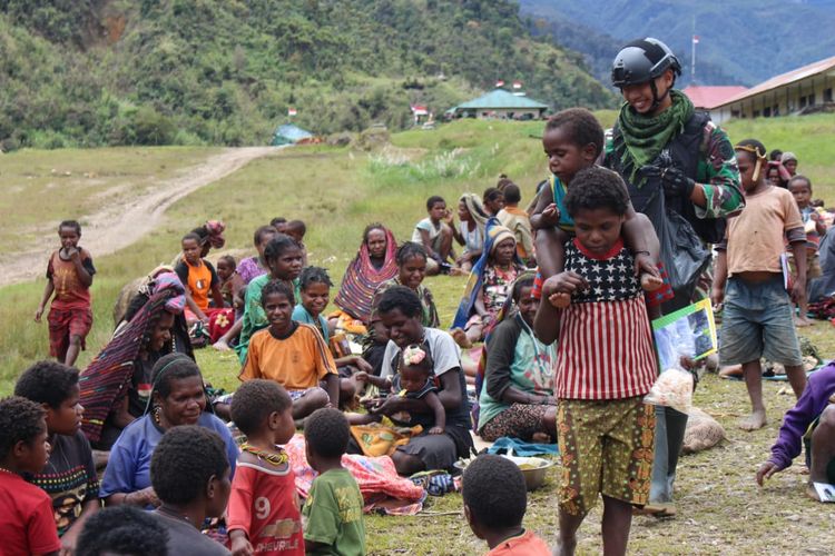 Tanpak prajurit TNI memberikan buku dan mengajak anak-anak di Distrik Mbua bermain games