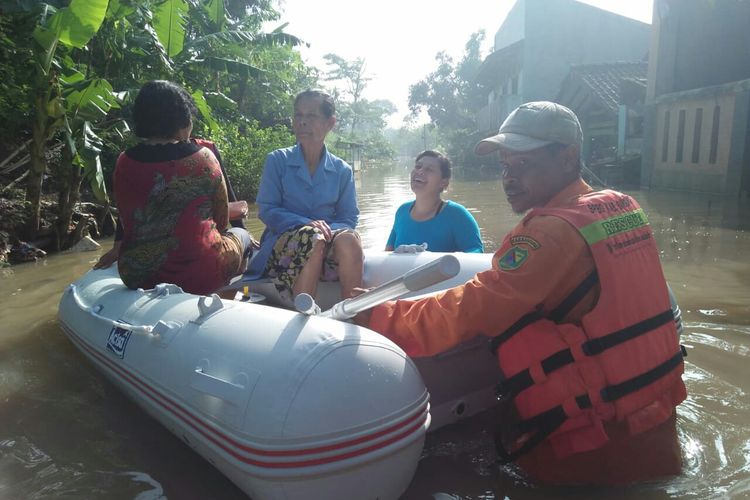 Petugas BPBD Kabupaten Bandung tengah mengantarkan warga korban banjir dengan perahu ke lokasi TPS yang jauhnya hingga 2 kilometer. 