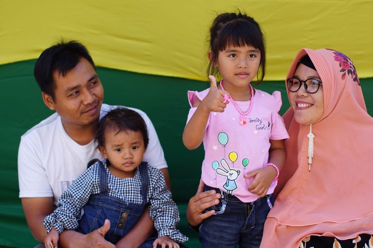 Salah satu anak yang akan menjalani pemotongan rambut gembel, Kayang Ayuningtiyas Nugroho (tengah), berfoto bersama keluarganya di rumah Tua Adat Ki Sumanto, di kawasan Dieng, Jawa Tengah, Sabtu (3/8/2019). 