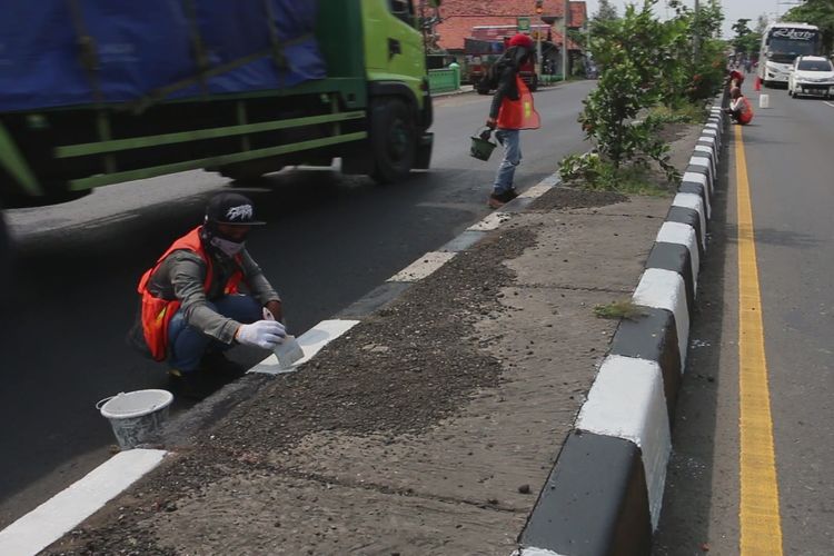 Wawan bersama tiga orang temannya mengecat median jalan di jalur pantura Losari Cirebon, Jawa Barat, Minggu (12/5/2019). Mereka kerja cepat untuk merampungkan pengecatan agar median jalan kembali jelas terlihat guna menghindari kecelakaan lalu lintas. 