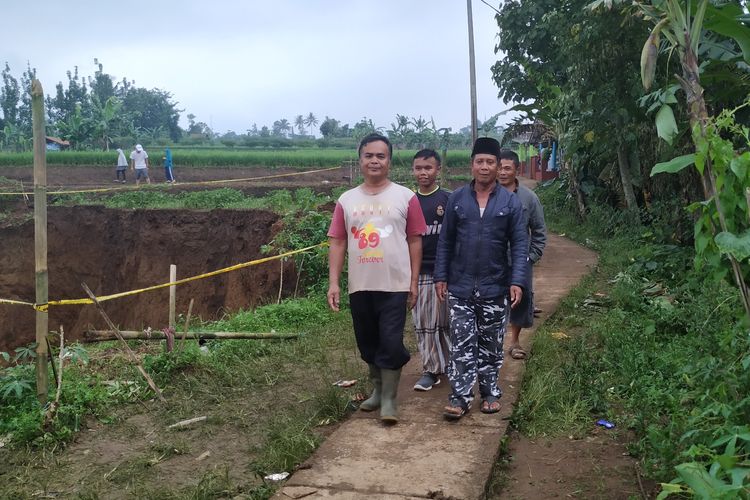 Sejumlah warga berjalan di pinggiran tanah amblas berbentuk lubang di Desa Sukamaju, Kadudampit, Sukabumi, Jawa Barat, Minggu (29/4/2019)