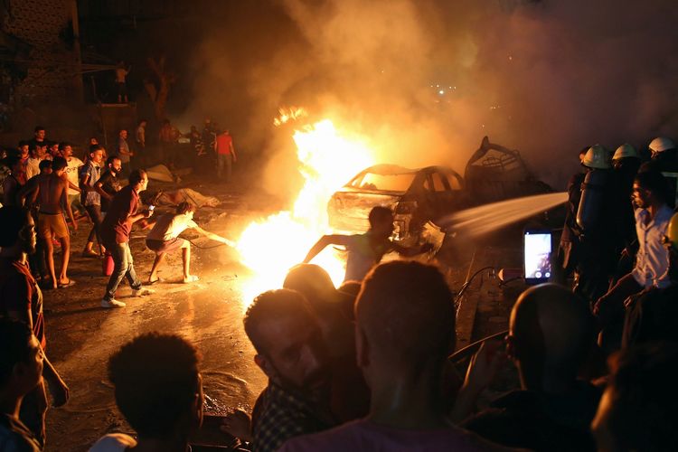 Warga setempat berusaha memadamkan api di mobil yang terlibat kecelakaan di Kairo, Mesir pada Minggu malam (4/8/2019). Sebanyak 19 orang tewas dalam insiden tersebut.
