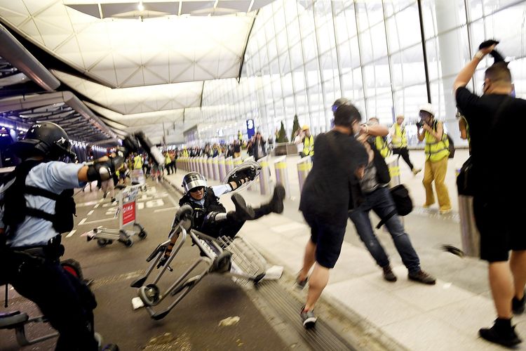 Seorang polisi terjengkang ketika menghadapi pendemo di Bandara Internasional Hong Kong 13 Agustus 2019. Penerbangan di bandara kembali dibatalkan buntut kelompok pro-demokrasi yang menguasai bandara selama dua hari beruntun,