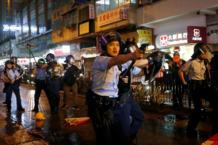 Anggota polisi menodongkan pistol ke arah peserta demo Hong Kong di Tsuen Wan, pada 25 Agustus 2019.