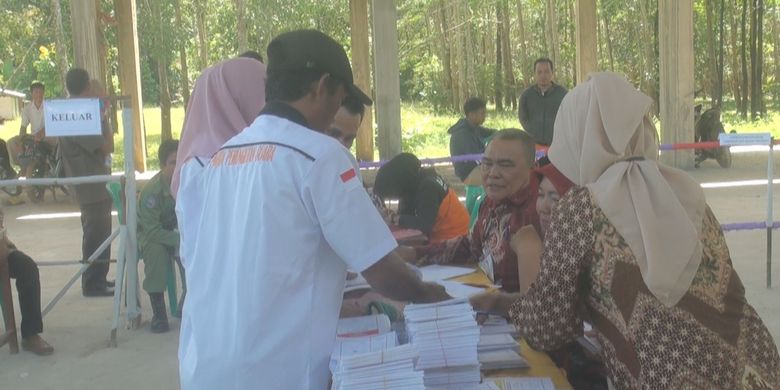 Ferdianto, anggota KPPS Patih Galung (kemeja putih) menyerahkan kertas suara untuk pemilihan presiden dan wakil presiden yang diproleh dari TPS sekitar ke petugas di TPS agar bisa digunakan oleh warga 