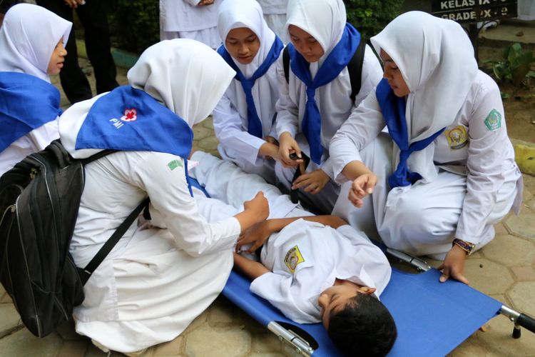 Tim kesehatan dari Palang Merah Remaja SMP Negeri 1 Banda Aceh, Kamis (17/12/2015), memberikan pertolongan pertama kepada siswa lainnya yang pingsan dalam latihan mitigasi bencana gempa dan tsunami. Sekolah tersebut ditetapkan sebagai sekolah percontohan siaga bencana.