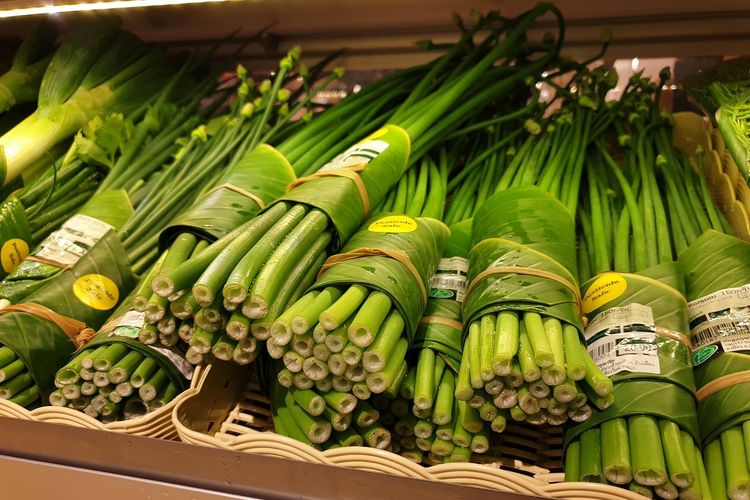 Daun dan bunga bawang dikemas menggunakan daun pisang di Rimping Supermarket.