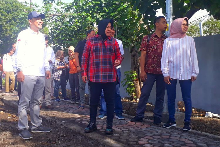 Wali Kota Surabaya, Tri Rismaharini, mengenakan setelan kemeja flanel, celana jins hitam, dan sepatu boots saat melakukan peninjauan beserta jajarannya di bantaran sungai Kali Jagir Surabaya, Sabtu (16/3/2019).