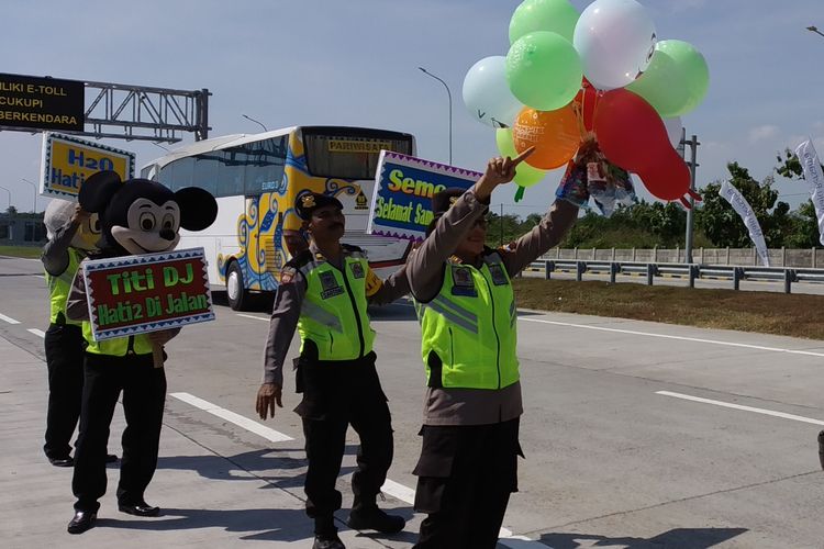 Anggota Sat Binmas Polres Karanganyar berkostum badut menghibur dan membagikan balon serta makanan kepada pemudik di pintu Tol Ngasem, Karanganyar, Jawa Tengah, Jumat (31/5/2019).