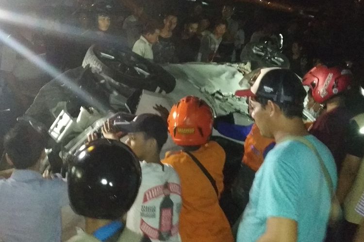 Petugas kepolisian dibantu warga mencoba mengevakuasi mobil Toyota Yaris yang tertabrak kereta api di perlintasan kereta api Purwosari, Solo, Jawa Tengah, Senin (20/5/2019) malam.
