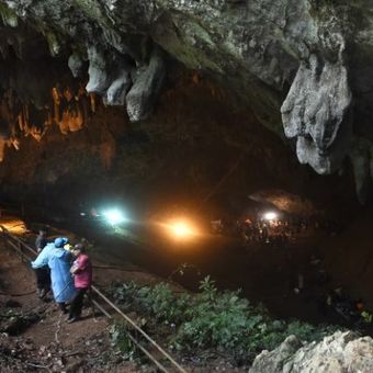 Tim penyelamat terlihat di depan gua Tham Luang di Taman Hutan Non Khun Nam Nang di Chiang Rai, Tabu (27/6/2018). Mereka berupaya menyelamatkan 12 remaja dan pelatih mereka yang hilang selama beberapa hari di dalam gua. (AFP/Lillian Suwanrumpha)