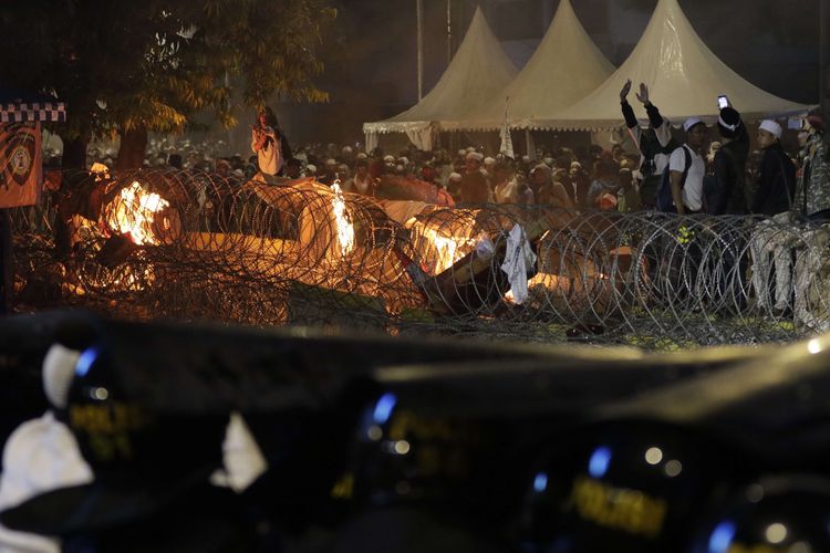 Polisi bertahan dari lemparan batu para demonstran yang ricuh di dekat gedung Bawaslu, Jalan MH Thamrin, Rabu (22/5/2019).