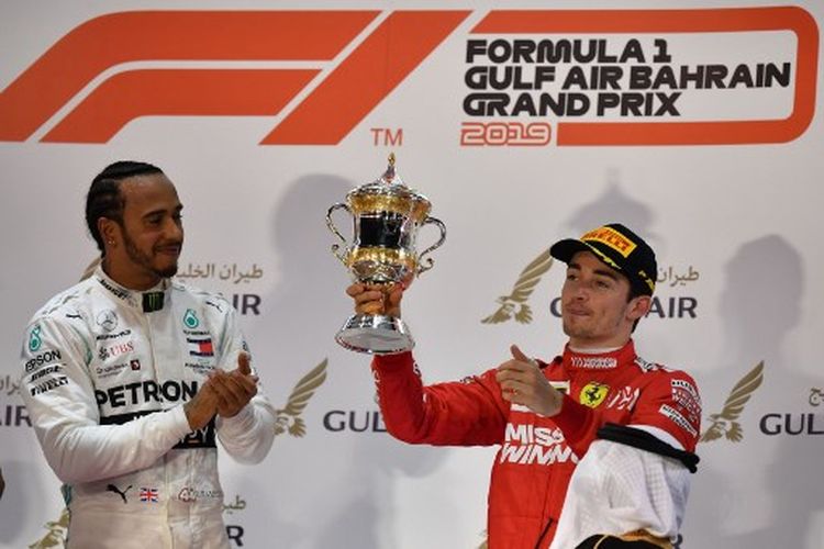 Pebalap Ferrari, Charles Leclerc (kanan), mengangkat trofi setelah finis urutan ketiga pada balapan GP Bahrain, di Sirkuit Sakhir, Bahrain, Minggu (31/3/2019).