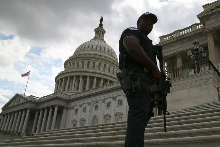 Seorang polisi terlihat bersenjata lengkap mengamankan gedung Capitol di Capitol Hill, Washington, Amerika Serikat, Senin (16/9/2013), menyusul penembakan di pangkalan Angkatan Laut Amerika Serikat yang berjarak kurang dari 3 kilometer dari gedung Senat Amerika ini.