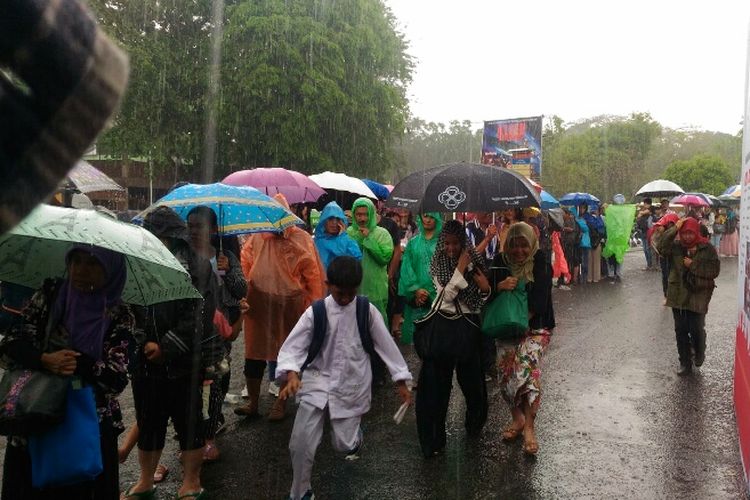 Kendati hujan turun di TMII, warga tetap mengantri untuk mencetak e-KTP, Jumat (20/10/2017).