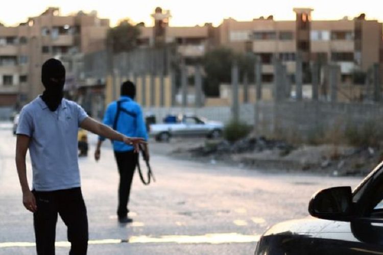 Dua orang anggota polisi ISIS menghentikan kendaraan di salah satu titik kota Raqqa, Suriah utara.
