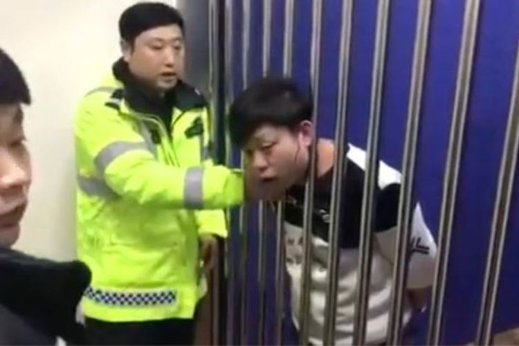 Kepala seorang pria yang ditahan di kantor polisi Harbin, China, entah bagaimana bisa terjepit di antara jeruji besi.
