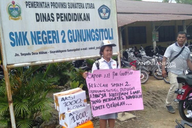 Anaria Mendrofa dengan membawa poster berdiri di depan sekolah di Gunungsitoli, Jumat (26/7/2019) 