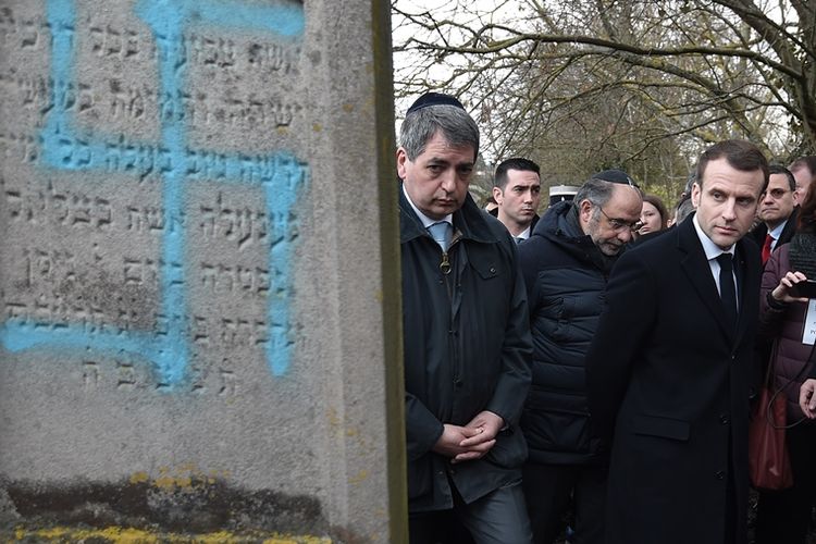 Presiden Perancis Emmanuel Macron melihat pemakaman yang dirusak dengan simbol swastika di pemakaman Yahudi di Quatzenheim, Selasa (19/2/2019). (AFP/FREDERICK FLORIN)