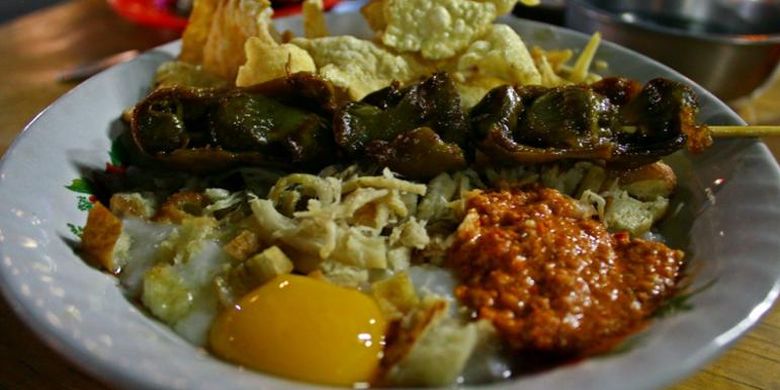 Bubur ayam spesial dengan tambahan kuning telur, emping, dan sate ampela.