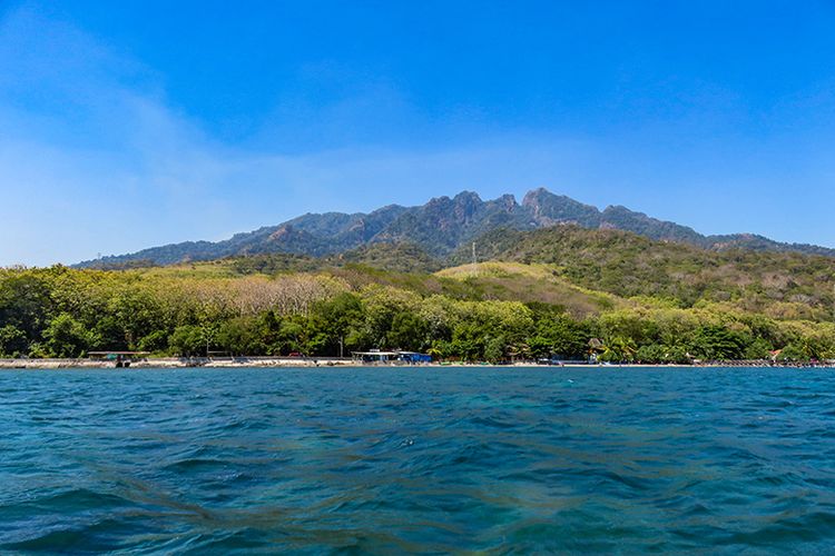Lanskap Pantai Pasir Putih Situbondo dengan latar belakang pegunungan.