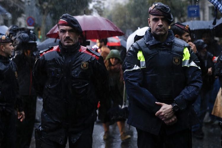 Petugas kepolisian lokal Catalonia, atau biasa disebut Mosso dEsquadra, berdiri menjaga demonstran warga Catalonia pro-kemerdekaan di depan delegasi pemerintah Spanyol di Barcelona, 19 Oktober 2017. 