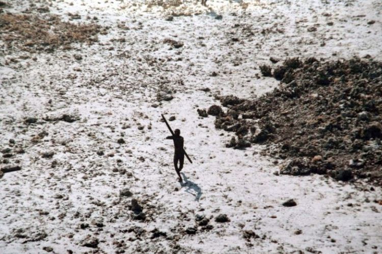 Foto ini diambil 28 Desember 2004 menunjukkan seorang pria suku Sentinel mengarahkan busur dan anak panahnya ke sebuah helikopter Pasukan Penjaga Pantai India saat terbang melintasi Pulau Sentinel Utara di Kepulauan Andaman. (AFP)