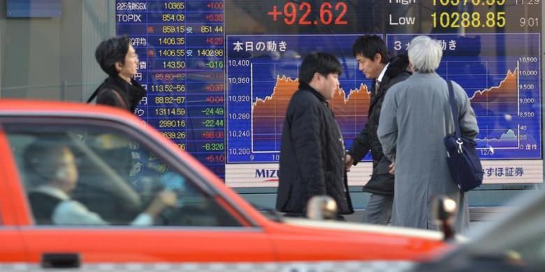Ilustrasi: Para pejalan kaki melewati sebuah papan elektronik yang memajang perkembangan di bursa saham Nikkei, Jepang.