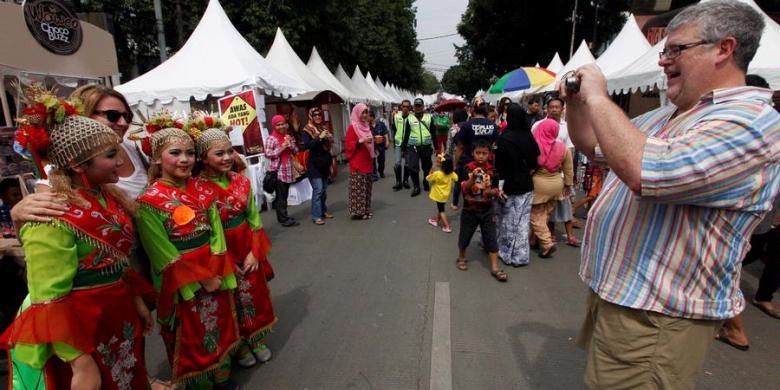 Pekerja ekspatriat berfoto dengan penari lenggang nyai di acara Festival Palang Pintu di Jalan Kemang, Jakarta, Sabtu (8/6/2013). Festival budaya dan kuliner Betawi tersebut telah diselenggarakan kedelapan kalinya dalam rangka HUT ke-486 DKI Jakarta dan akan berlangsung 8-9 Juni 2013. KOMPAS/LUCKY PRANSISKA