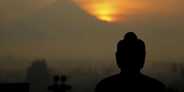 Pemandangan matahari terbit dari balik Gunung Merapi dengan latar depan patung Buddha di Candi Borobudur, Magelang, Jawa Tengah, Rabu (20/4/2011). Wisatawan yang ingin melihat pemadangan matahari terbit harus ada di candi pukul 04.30. Wisatawan lokal dikenakan biaya Rp 220.000.