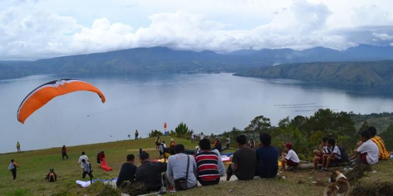 Penduduk menonton atraksi paralayang di Bukit Siulakhosa, Pulau Samosir, Sumatera Utara. Paralayang merupakan rangkaian kegiatan Festival Danau Toba 2013 yang digelar 8?14 September 2013.