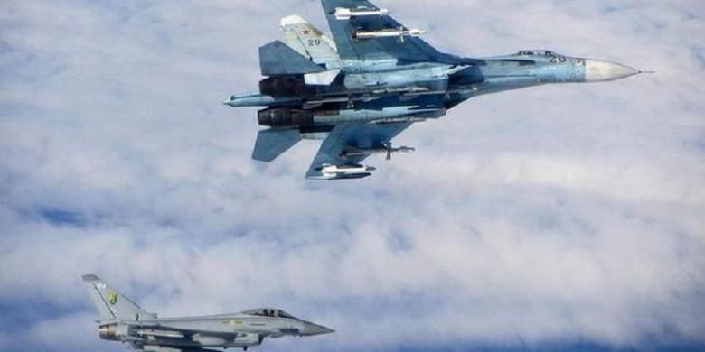 Sebuah pesawat tempur Sukhoi Su-27 (atas) milik Rusia diawasi sebuah pesawat tempur Royal Air Force (RAF) Typhoon Inggris (bawah) saat sejumlah pesawat militer Rusia terbang di wilayah udara internasional dekat negara-negara Baltik, Senin (16/6/2014)
