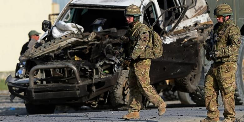 Beberapa prajurit AS berjalan melintasi sebuah mobil yang hancur akibat serangan bom bunuh diri Taliban di Kabul, Afganistan, Senin (13/10/2014).