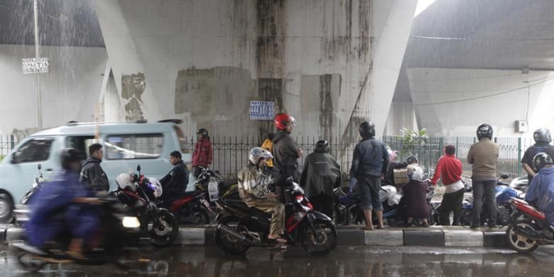 Pengendara motor berteduh di bawah jembatan di kawasan Slipi, Jakarta, Jumat (14/11/2014). Badan Meteorologi, Klimatologi, dan Geofisika (BMKG) memperkirakan wilayah DKI Jakarta diguyur hujan dengan intensitas ringan hingga sedang pada siang hingga malam hari. KOMPAS IMAGES/RODERICK ADRIAN MOZES