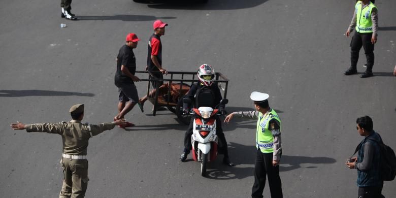 Gabungan petugas kepolisian dan Dinas Perhubungan DKI mengarahkan pengendara sepeda motor yang akan melintas di Jalan MH Thamrin, Jakarta Pusat, Rabu (17/12/2014). Di hari pertama uji coba pembatasan sepeda motor sepanjang Jalan Thamrin-Medan Merdeka Barat, masih terdapat sejumlah pengendara yang belum mengetahui aturan tersebut. KOMPAS/LUCKY PRANSISKA 