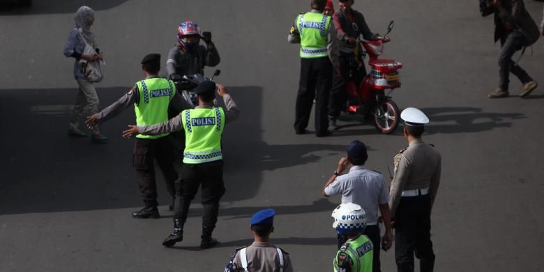 Gabungan petugas kepolisian dan Dinas Perhubungan DKI mengarahkan pengendara sepeda motor yang akan melintas di Jalan MH Thamrin, Jakarta Pusat, Rabu (17/12/2014). Di hari pertama uji coba pembatasan sepeda motor sepanjang Jalan Thamrin-Medan Merdeka Barat, masih terdapat sejumlah pengendara yang belum mengetahui aturan tersebut. KOMPAS/LUCKY PRANSISKA 