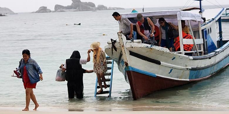 Wisatawan turun dari perahu motor yang mengantar mereka mengunjungi beberapa pulau di perairan dekat Pantai Tanjung Kelayang, Kabupaten Belitung, Kepulauan Bangka Belitung, Kamis (18/12/2014). Hujan sejak pagi tidak menyurutkan sejumlah wisatawan mengunjungi pulau-pulau menawan di kawasan itu, seperti Pulau Lengkuas dan Kepayang.