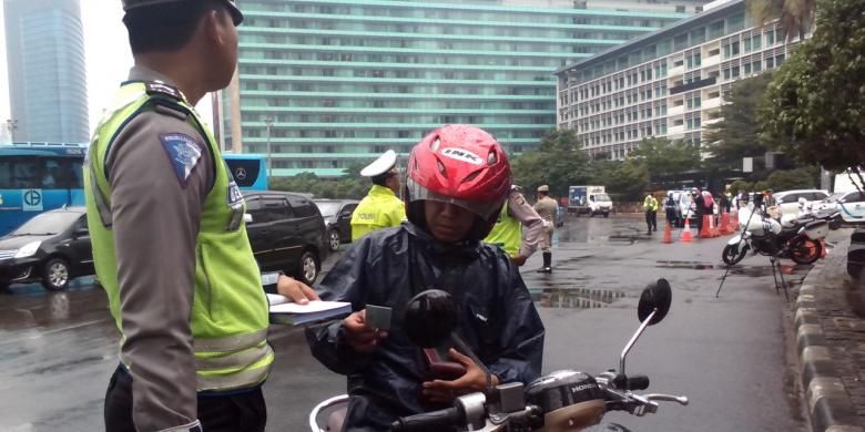 Saah seorang pengendara motor ditilang karena mencoba menerobos jalur pelarangan sepeda motor di Jalan M.H Thamrin, Jakarta Pusat, Senin (19/1/2015).