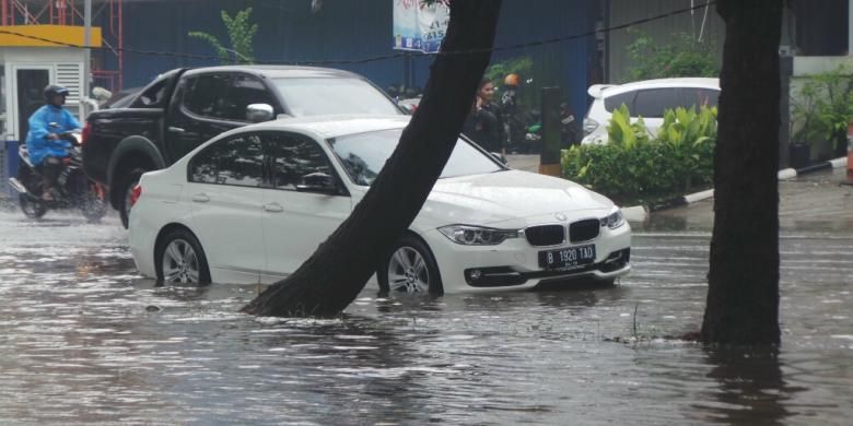 Diduga mogok karena banjir, sedan BMW bernomor polisi B 1920 TAD berwarna putih terjebak di tengah banjir yang menggenangi Jalan Boulevard Barat, Kelapa Gading, Jakarta Utara, Jumat (23/1/2015).