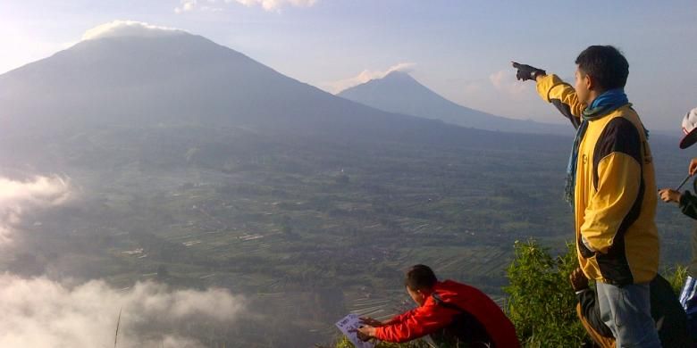 Salah seorang pendaki menunjukkan Gunung Merbabu dan Gunung Merapi saat matahari terbit, Minggu (5/4/2015) pagi.